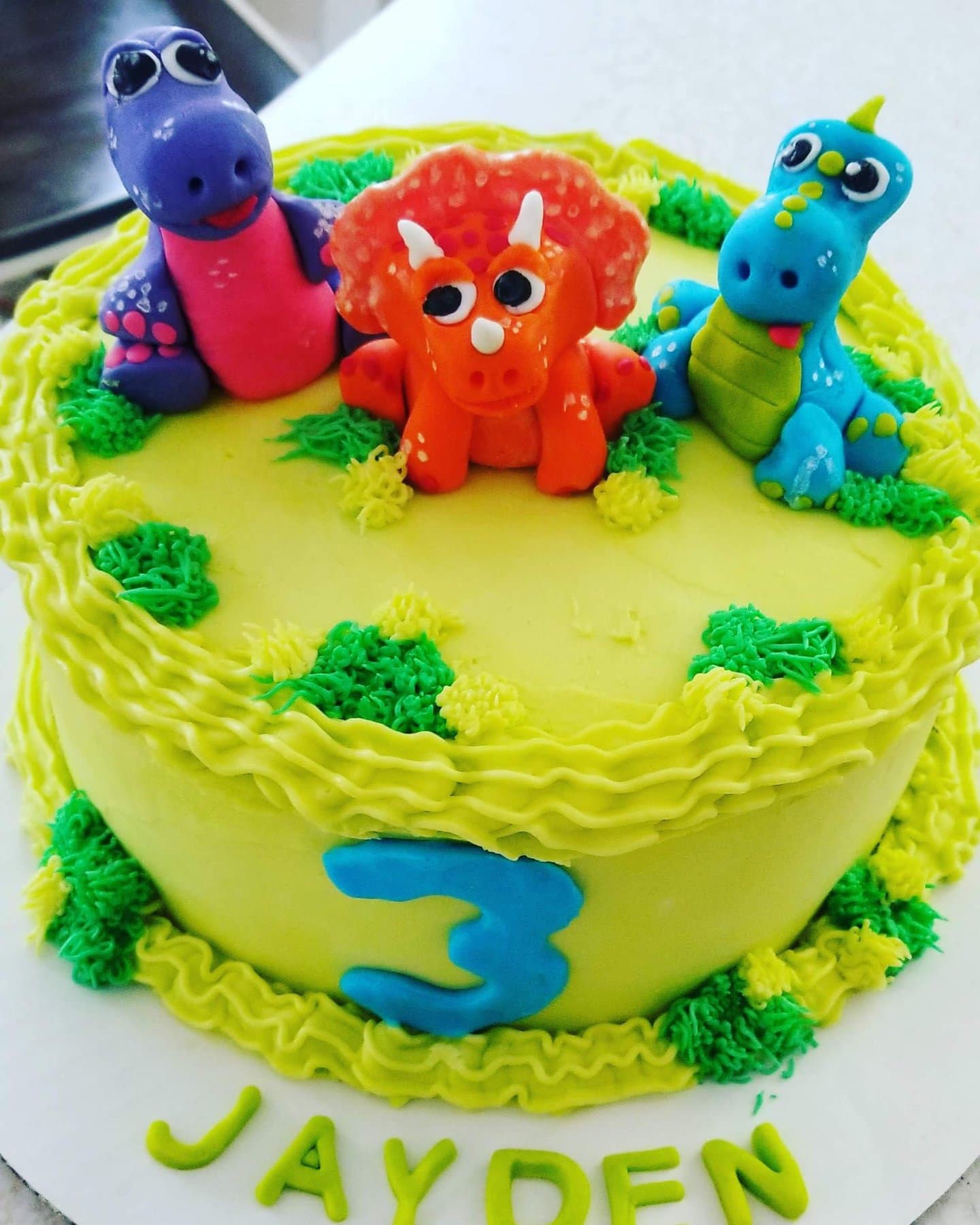 Colorful dinosaur birthday cake with bright toppers by Jamie Cakes.