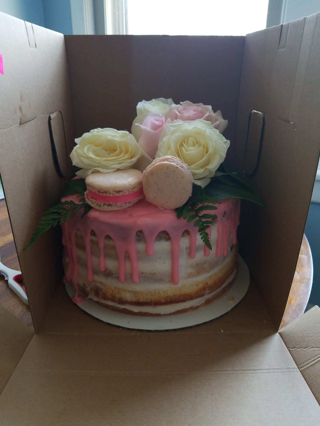 Pink drip cake with roses and macarons by Jamie Cakes.