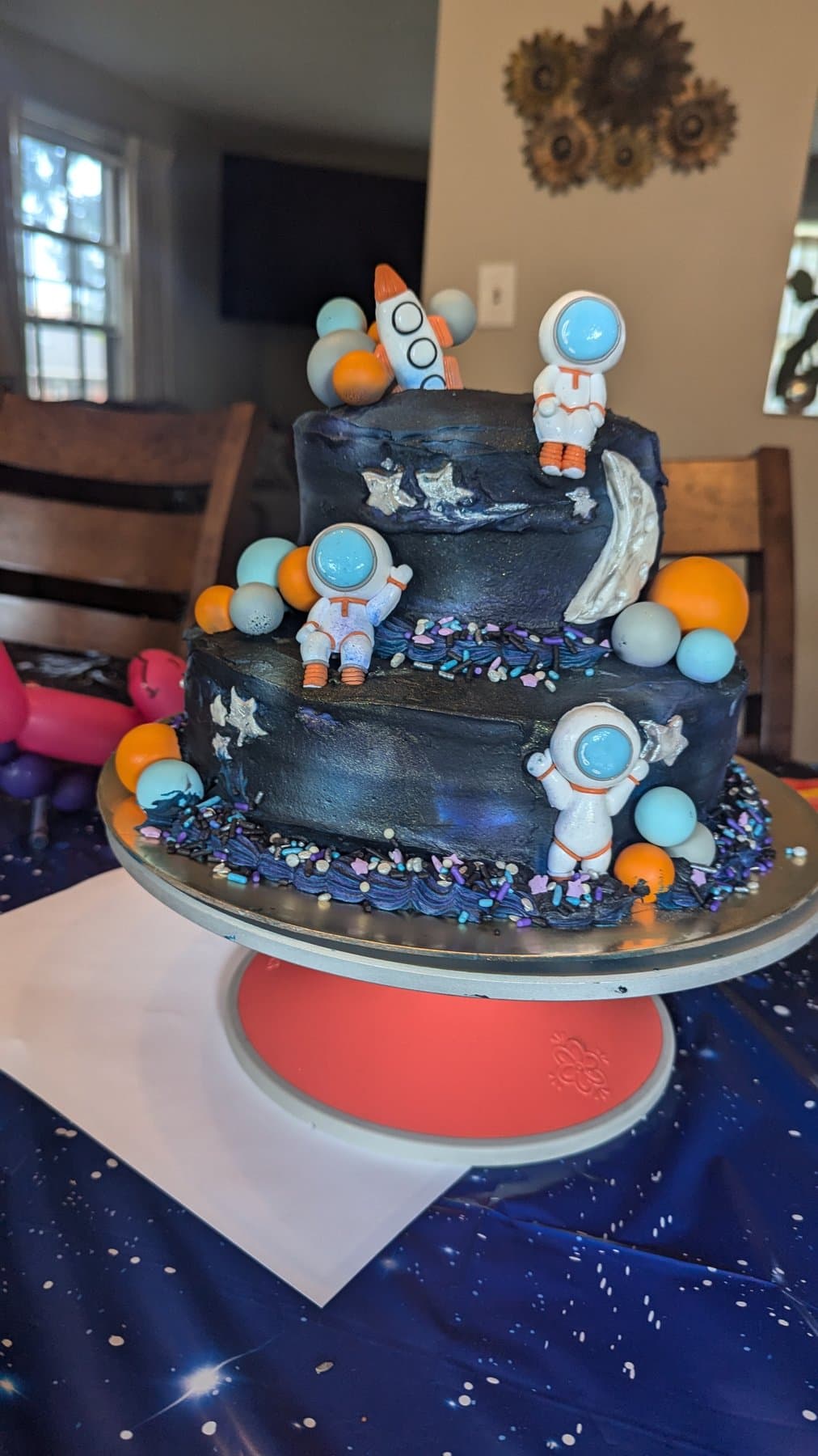 Space-themed birthday cake with astronaut toppers and planet decorations by Jamie Cakes.