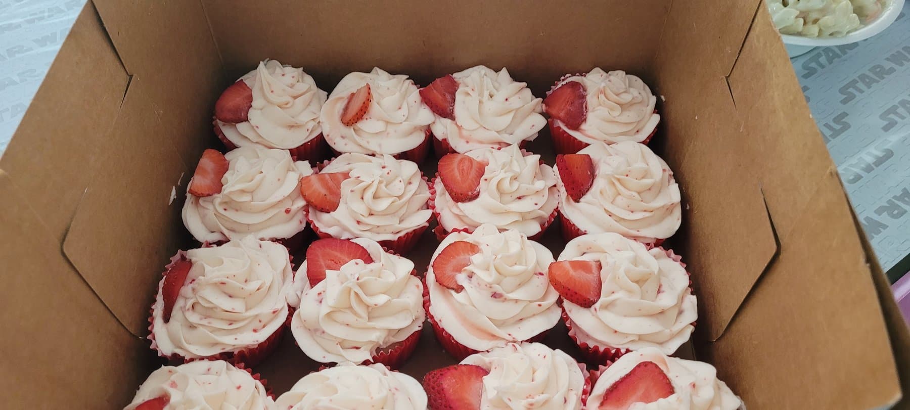 Strawberry cupcakes with pale pink buttercream and fresh strawberry slices by Jamie Cakes.